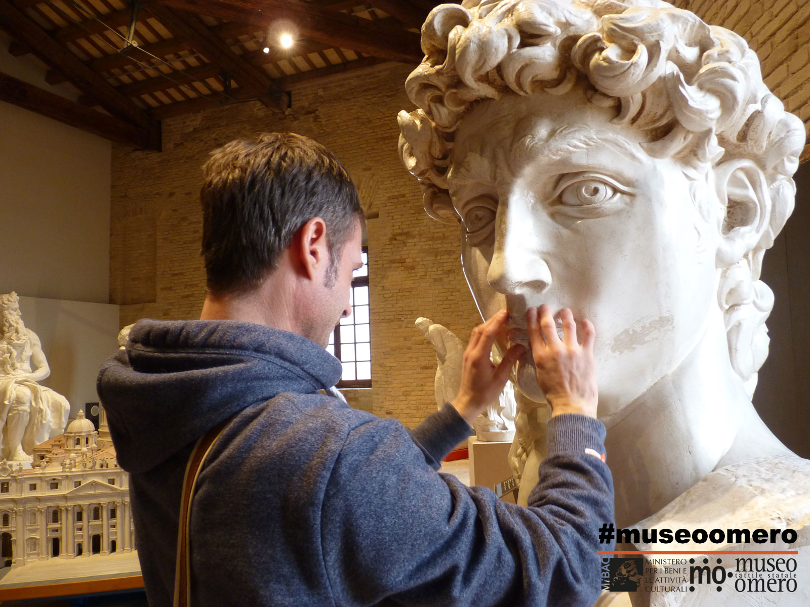 Mani che toccano la testa del David di Michelangelo a scala reale